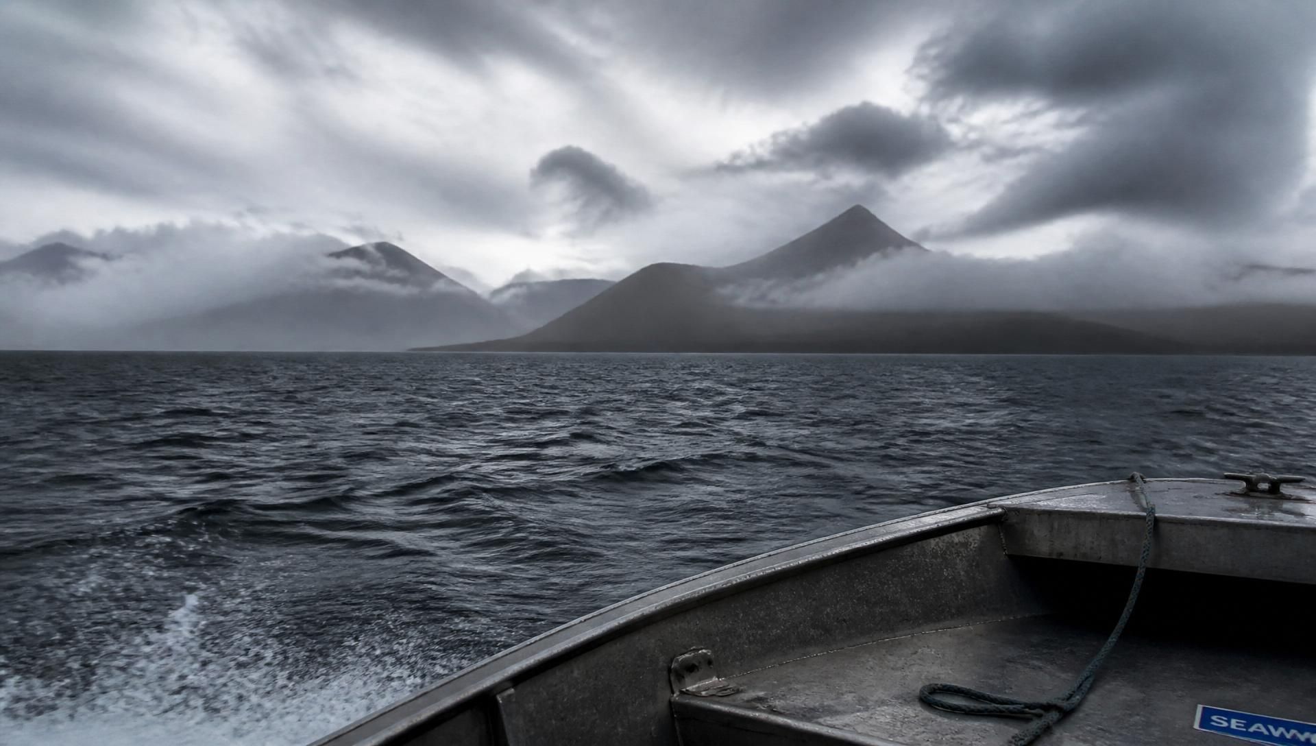 Yacht anchored in a Kodiak Island bay with green mountains rising into low cloud
