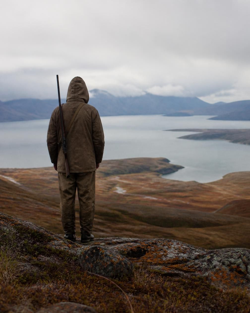 Hunter in raingear glassing an alder-choked ridge on Kodiak Island